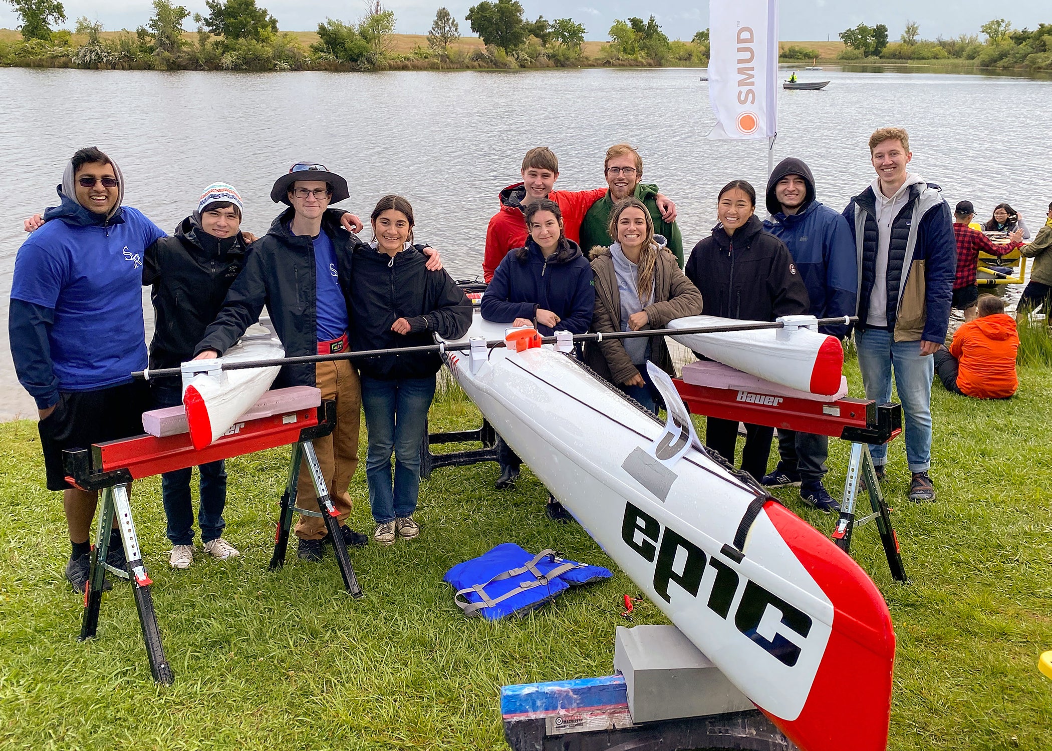 Cal Poly Solar Regatta Club members gather around their award-winning boat at 2023 California Solar Regatta, at a lake near Sacramento