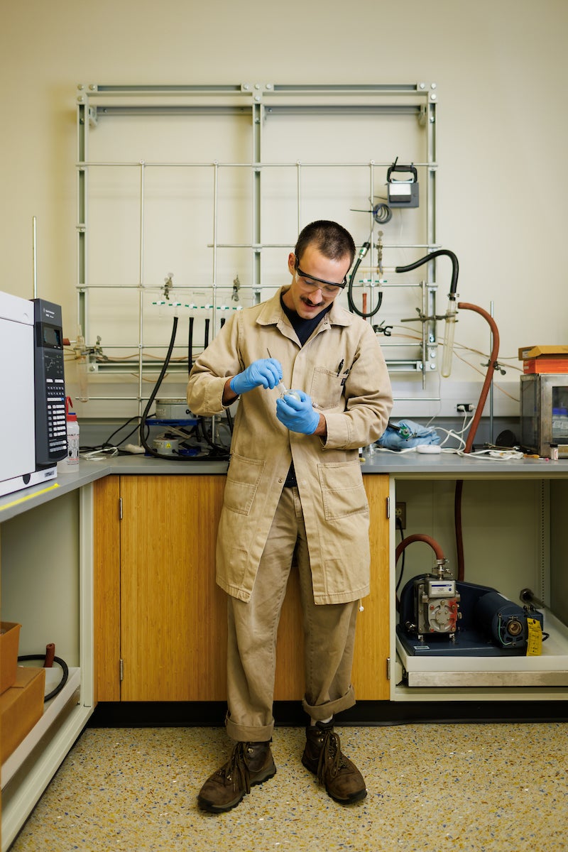 Chemistry student Sal Deguara wears protective gear as he inspects a compound he is working with.