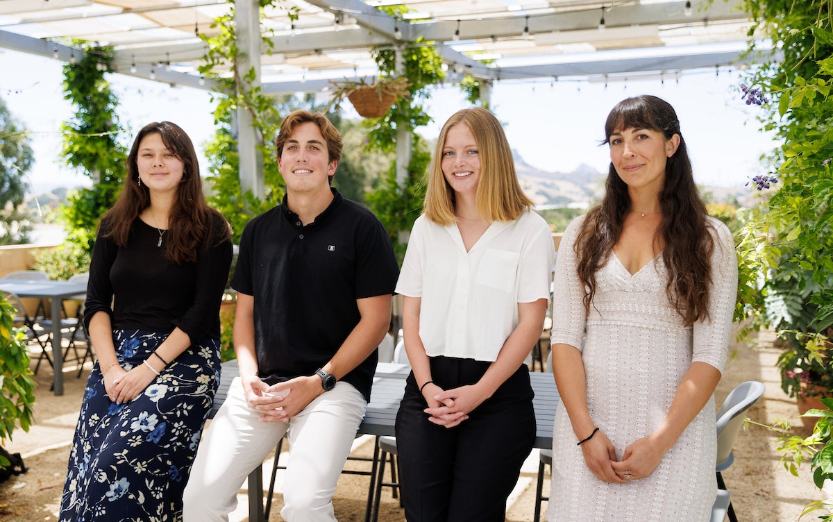 Four students involved with the project smile for a photo outside on the Plant Conservatory's patio..