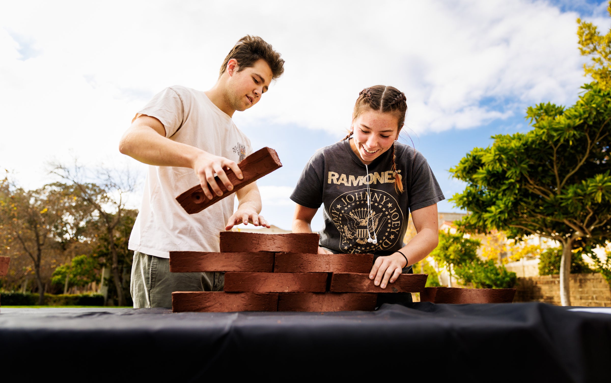 Two students stack handmade bricks on top of each other during an event on Dexter Lawn.