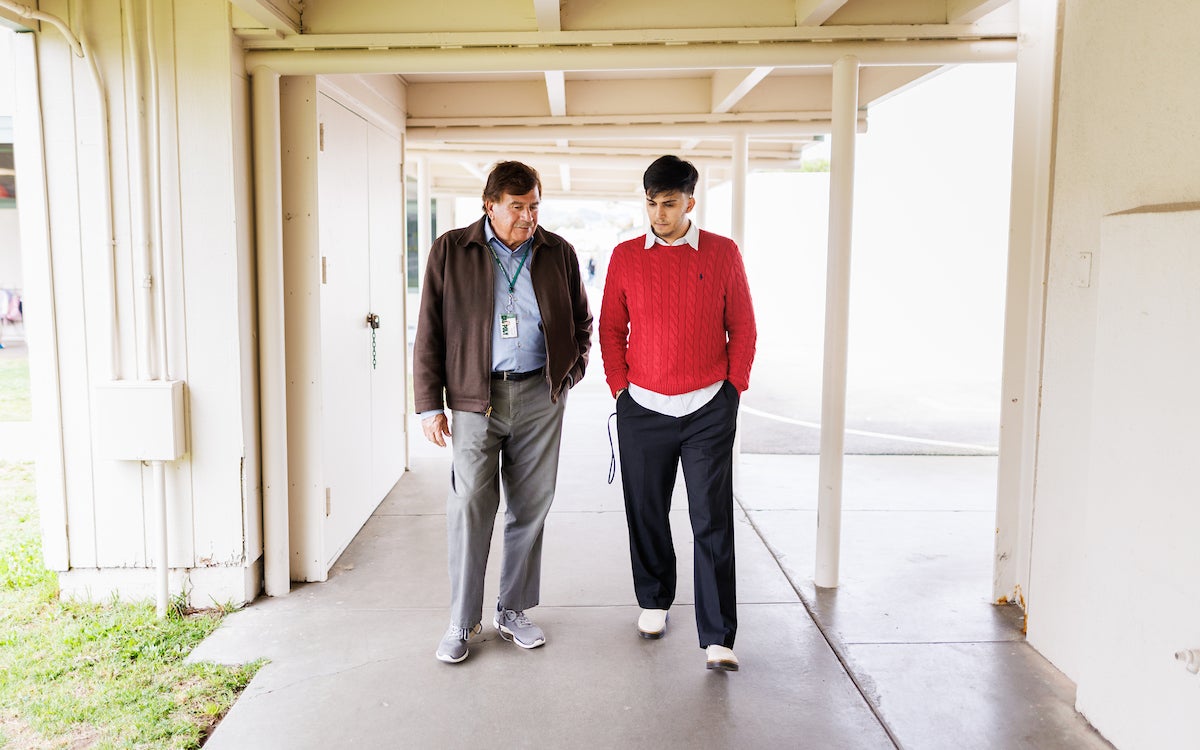 Juan Olivarria and Ramon Gutierrez, both dressed in business casual, walk through a breezeway.