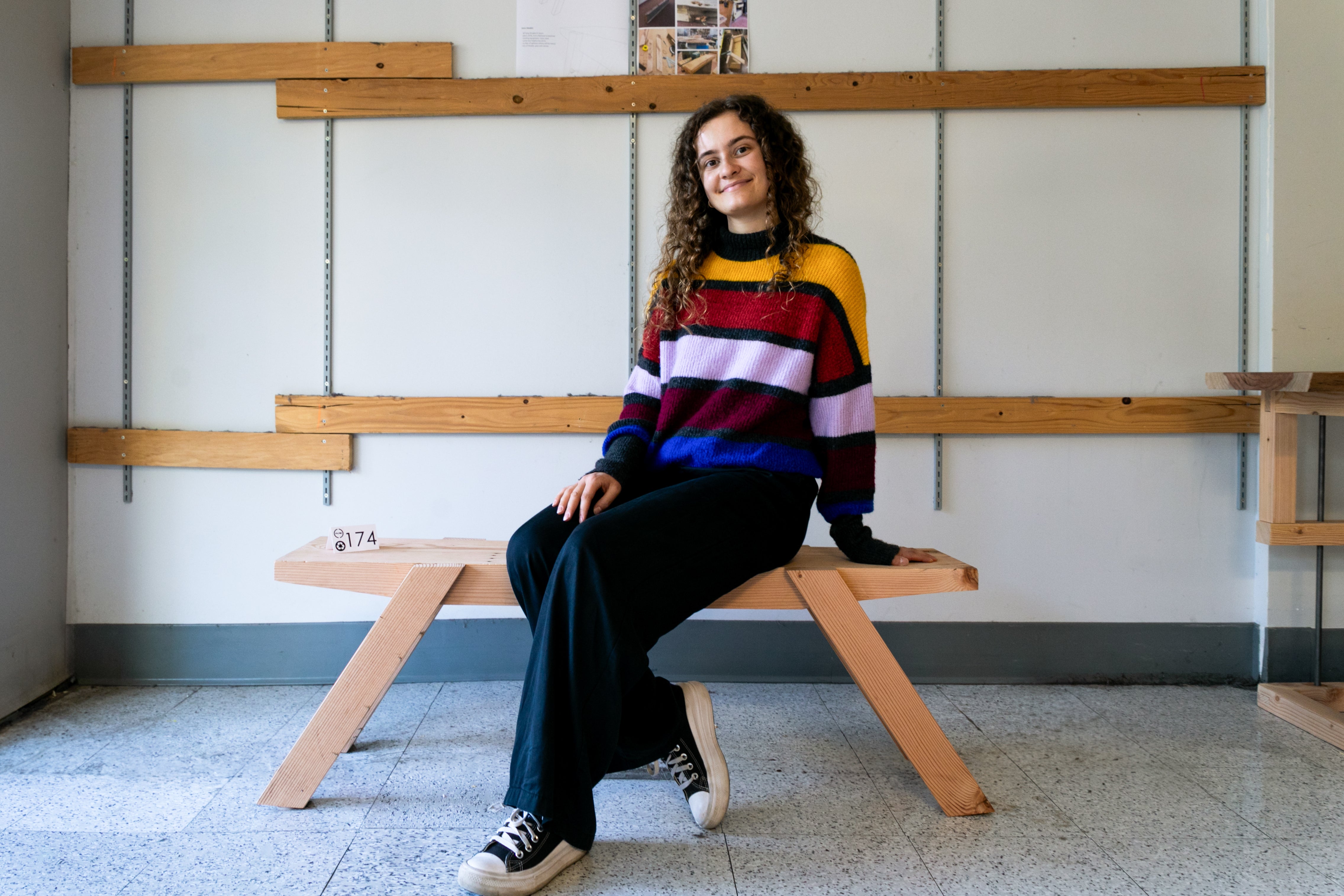 A student poses on a wooden bench.