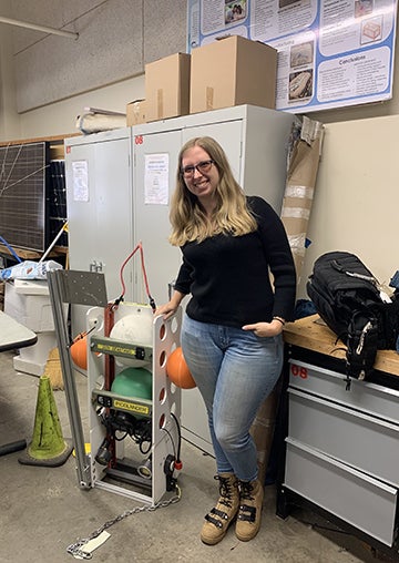 Master's student Nikki Arm stands next to the lander she developed.