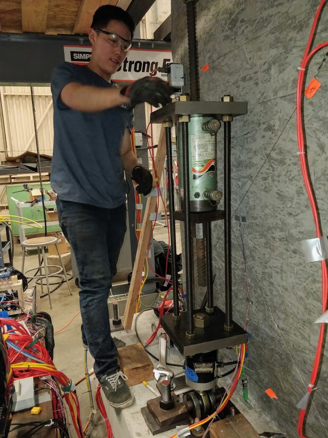 Graduate student researcher Jerry Luong makes final adjustments to the axial load system before testing a concrete wall in 2019