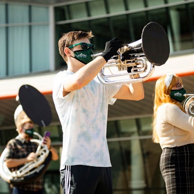 A member of the Cal Poly Band wears a mask while playing an instrument with MERV-13 filtration material on the bell cover