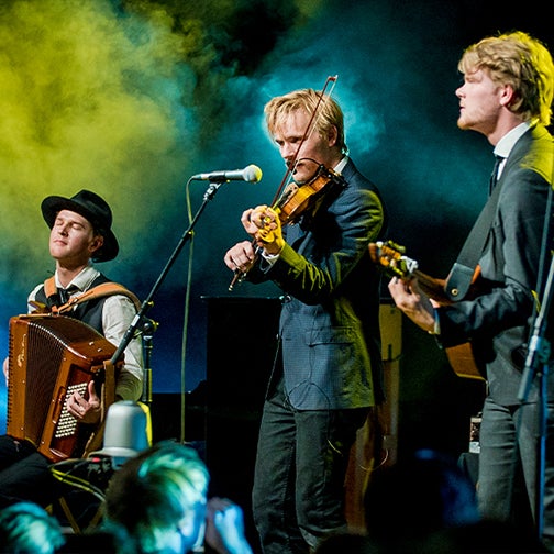 A group of three men from Dreamers Circle play various instruments on stage