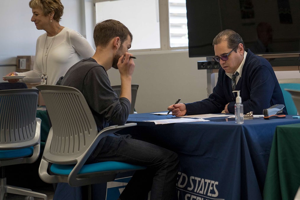 A USPS employee helps Cal Poly student receive a free passport at the 2020 Passport Event 