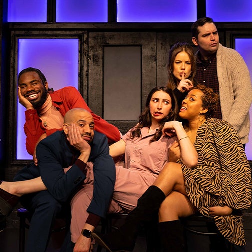  Six performers posing on stage making various facial expressions