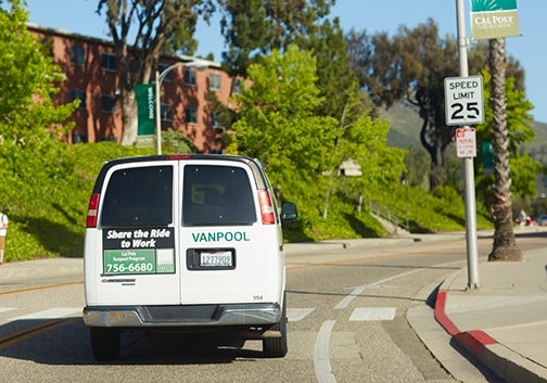 A van reading "Vanpool" drives by the red brick residence halls on the Cal Poly campus.