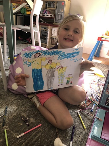 Preschool student Evelyn poses with a craft she made in the Preschool Learning Lab