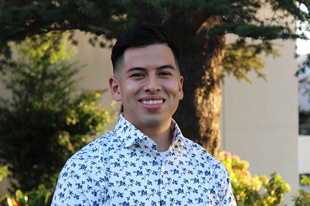 A young man smiling in a white button up shirt