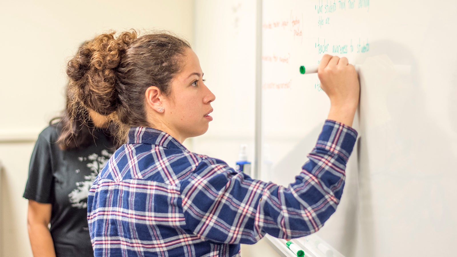 Student works on math problem on a whiteboard. 