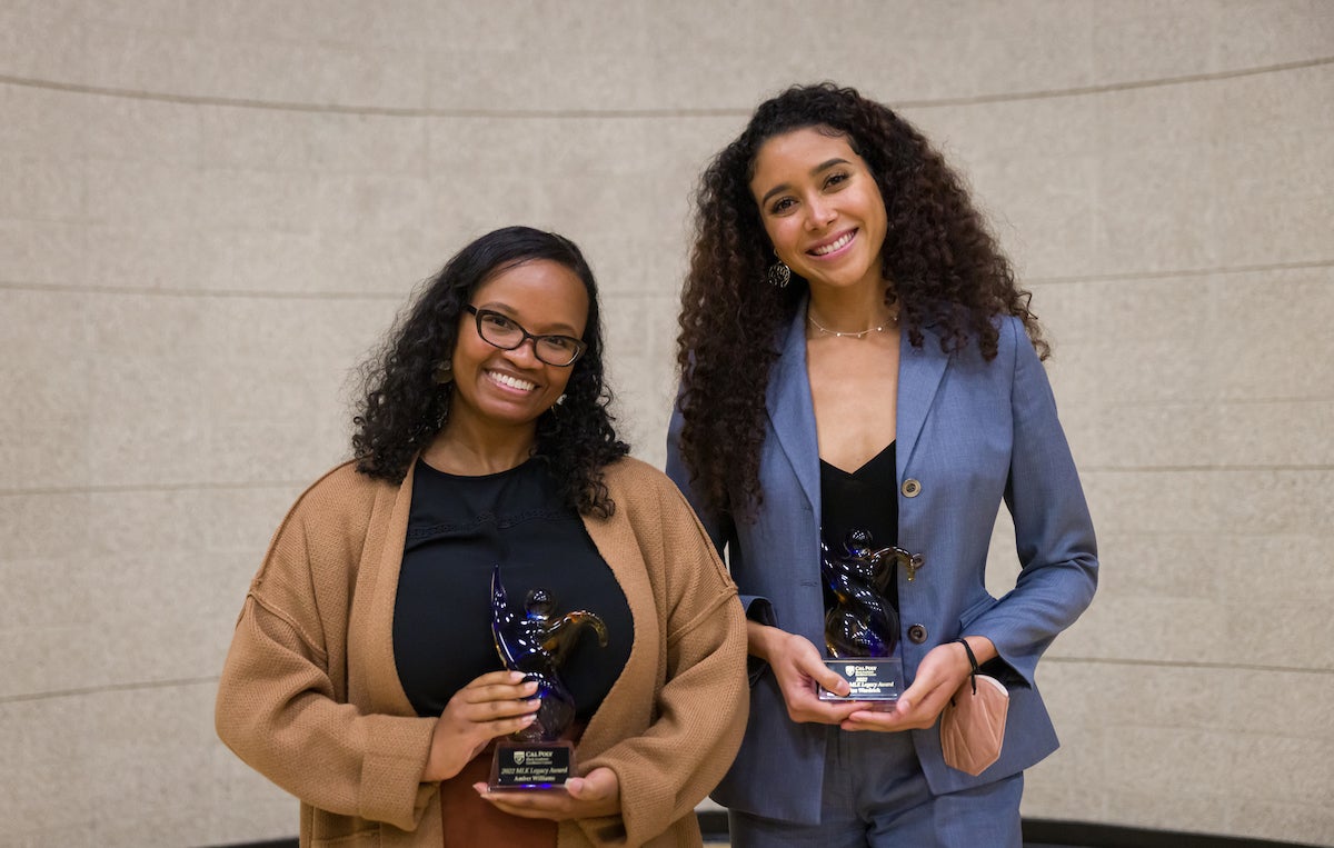 Two women smile while holding trophies