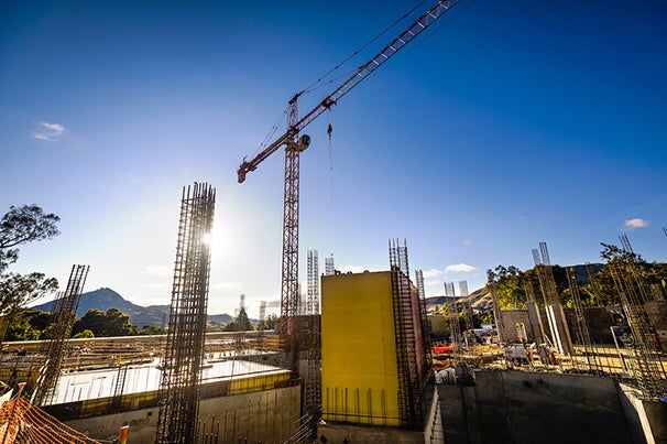 The sun rises over cranes and other heavy machinery at a construction site on campus.