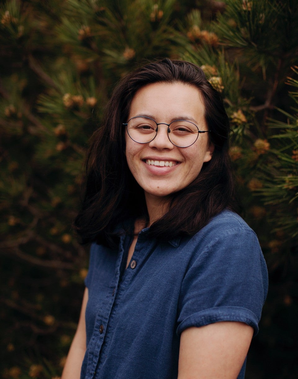 Nayl Gonzalez, smiling in front of foliage