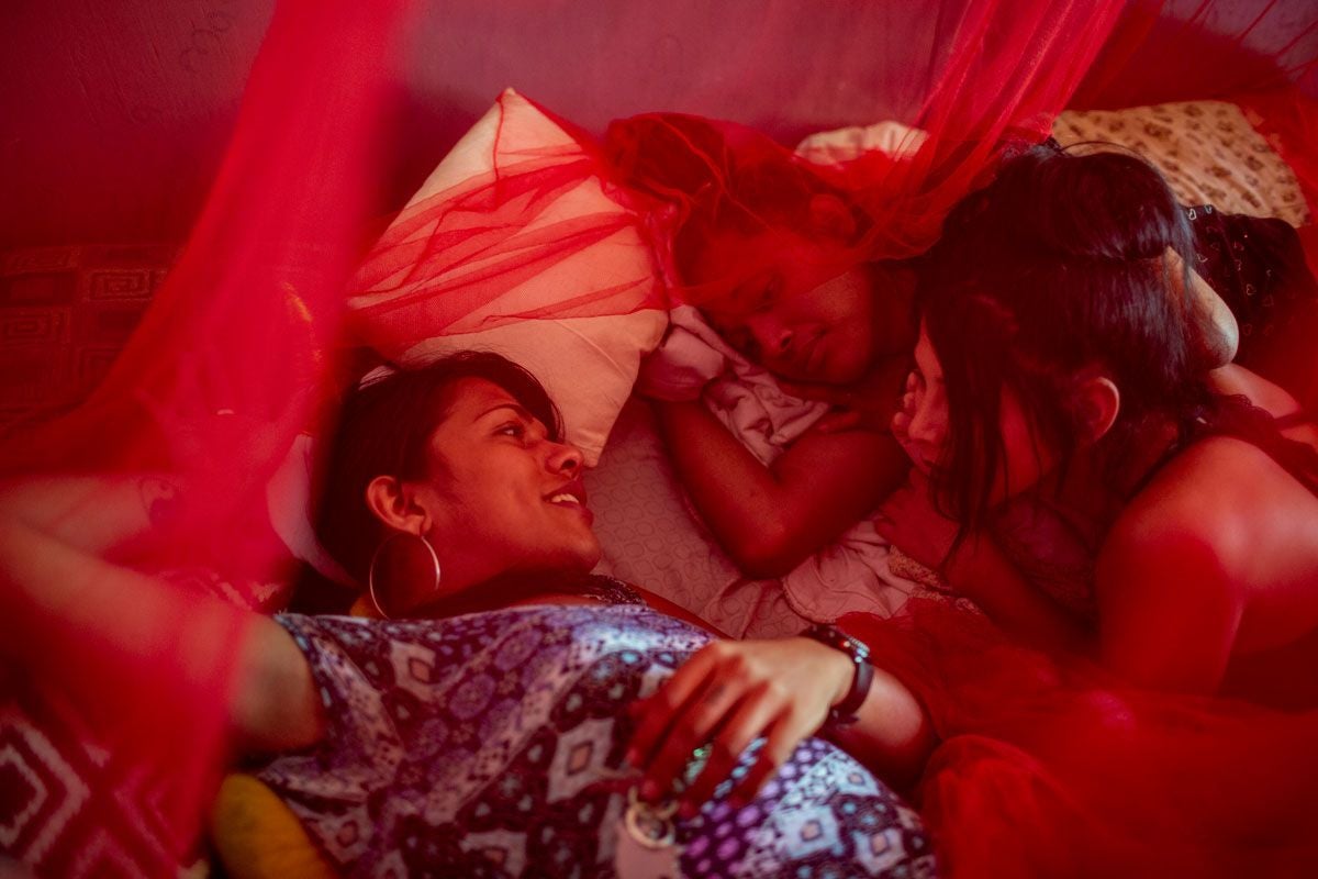 Group of people lying on a bed chatting.