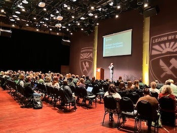 Terrance Harris speaks on stage to a group of faculty and staff for the SEM Summit.