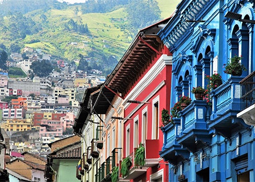 Colorfully painted two-story residences give way to a hillside of homes 