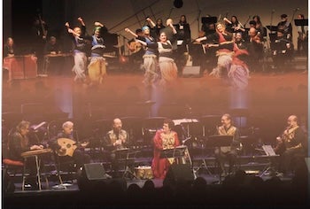 Performers dance and play instruments on stage.