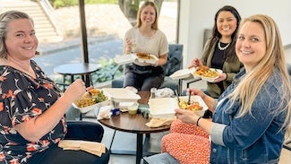 Employees eat lunch together around a table.