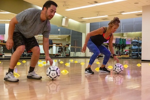 Indoor group fitness class works out with soccer balls.