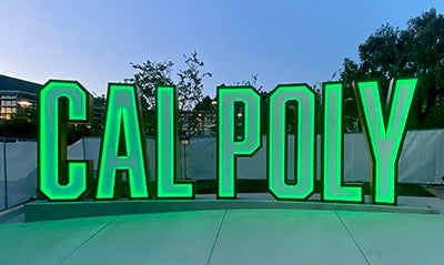 The Cal Poly letters in the university union are shown lit at twilight