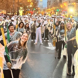 Band stands in street with instruments and smiles.