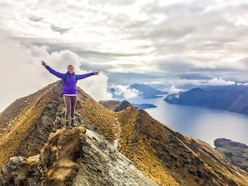 Woman on top of a mountain with hands in the air.