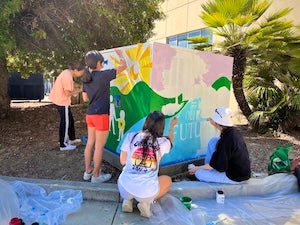 Students paint a colorful utility box together.