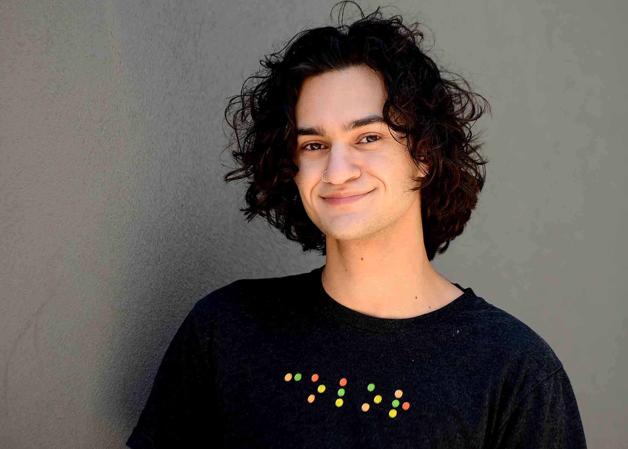 A professional headshot of soon-to-be graduate M.W. Kaplan, wearing a black T-shirt.