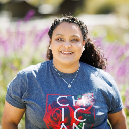 Cheryl Flores smiles on a sunny day near purple Mexican sage plants