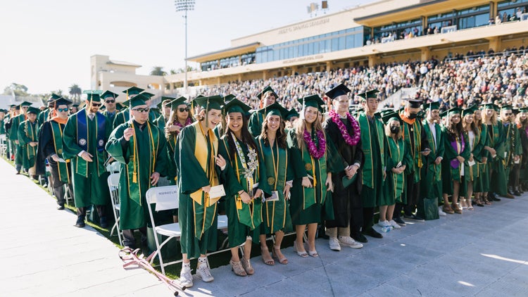 Rows of graduates smile in a stadium 