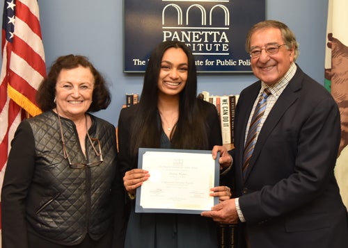 Three people stand holding a certificate in front of an American flag, a California State flag, and a blue sign reading 'Panetta Institute: the institute for public policy'