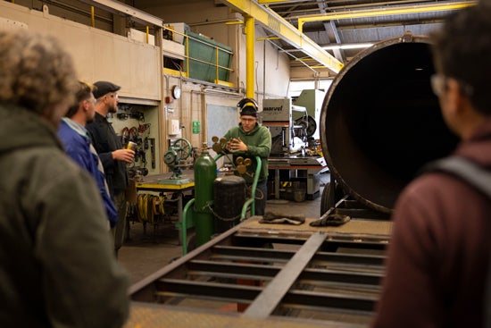 People wearing safety glasses stand around equipment and machinery in an agricultural engineering lab