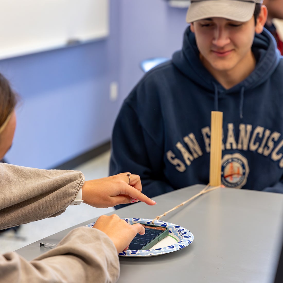 Students use a phone on a paper plate to conduct an experiment.