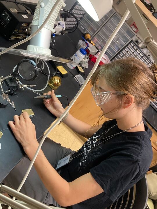 Reagen Garcia wears goggles as she works with scientific equipment.