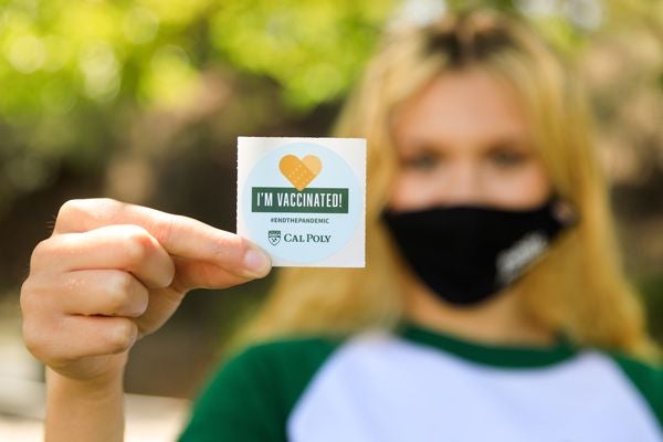 Student holding a sticker that says "I'm Vaccinated"