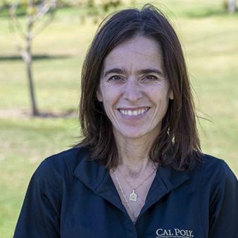 A woman in a black polo shirt smiles into the camera.