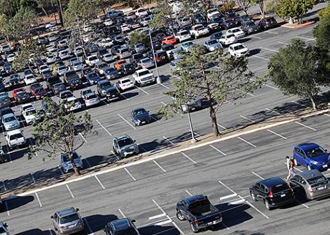 An aerial photo of a Cal Poly parking lot showing a student walking across a parking lot 