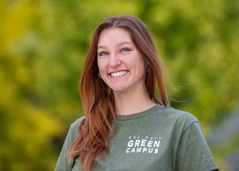 Graduate student Kalea Conrad poses in front of a stand of yellow and green foliage