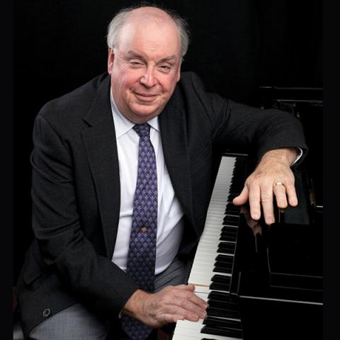 Portrait of pianist and Cal Poly music Professor Emeritus W. Terrence Spiller seated at a piano