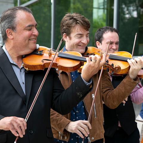  Three men in suits play their strings instruments