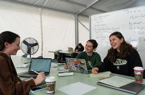 A group of students interact while seated at a table in a Kennedy Library temporary study space