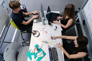 Students work on computers at a table.