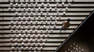 Cal Poly student walking up staircase adorned with design-build models. 