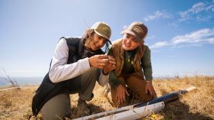 Two students take a soil sample on an oceanside cliff on a sunny day at Swanton Pacific Ranch