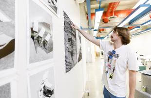 A student in a white t-shirt points to architectural drawings regarding the Salinas Dam on a wall.