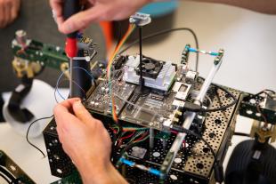 A student adjusts wires on a capstone project in a computer engineering class.