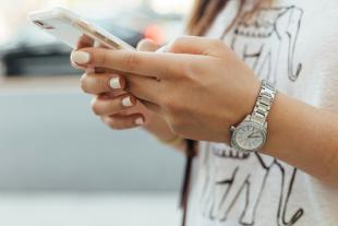 A woman holds and uses a phone.