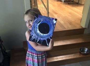 Preschooler Evelyn poses with a painting she made as part of the Preschool Learning Lab.